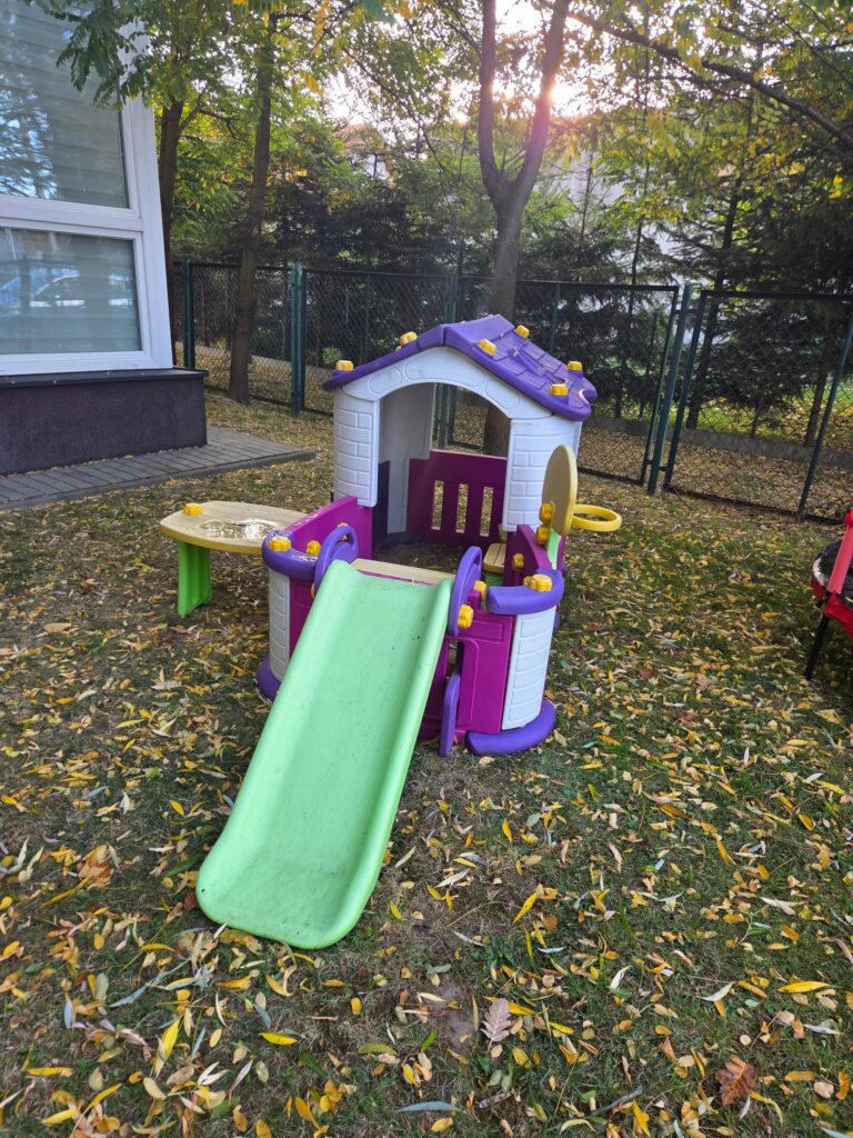Pusty ogród żłobka z kolorowym domkiem i zjeżdżalnią