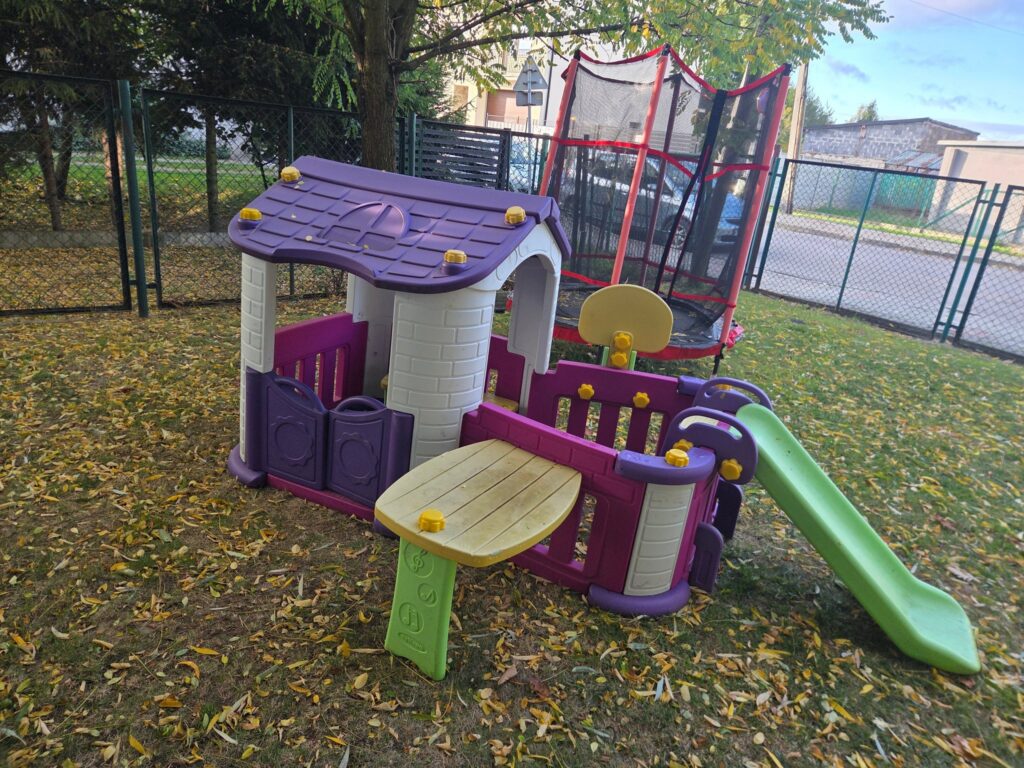 Puste urządzenia do zabawy oraz trampolina w ogrodzie żłobka